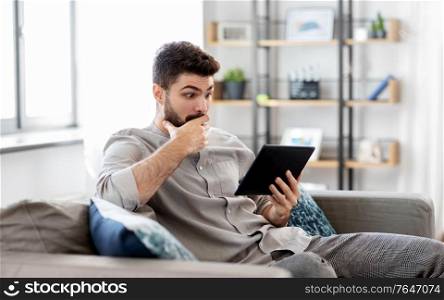 technology, people and lifestyle concept - shocked man with tablet pc computer at home. shocked man with tablet computer at home