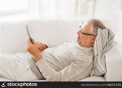 technology, people and lifestyle, distance learning concept - senior man with tablet pc computer lying on sofa at home