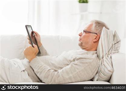 technology, people and lifestyle, distance learning concept - senior man with tablet pc computer lying on sofa at home