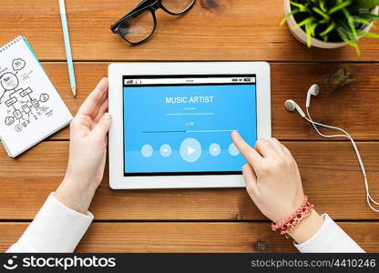 technology, people and multimedia concept - close up of woman with music media player on tablet pc computer screen on wooden table