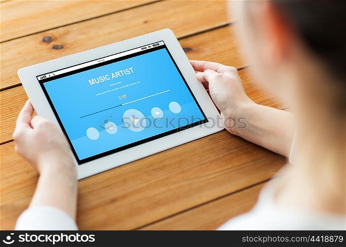technology, people and multimedia concept - close up of woman with music player on tablet pc computer screen on wooden table
