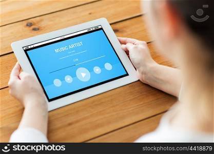 technology, people and multimedia concept - close up of woman with music player on tablet pc computer screen on wooden table