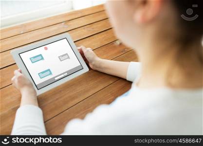 technology, people and online communication concept - close up of woman with messenger or internet chat on tablet pc computer screen on wooden table