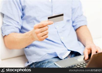 technology, people and online shopping concept - close up of man with laptop computer and credit card at home
