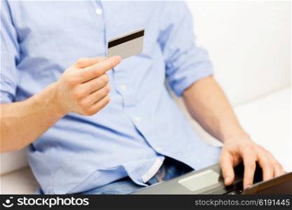 technology, people and online shopping concept - close up of man with laptop computer and credit card at home