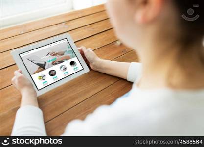 technology, people and online shopping concept - close up of woman with internet shop web page on tablet pc computer screen on wooden table