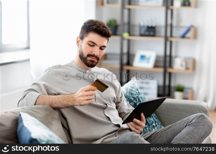 technology, people and online shopping concept - man with tablet pc computer and credit card at home. man with tablet computer and credit card at home