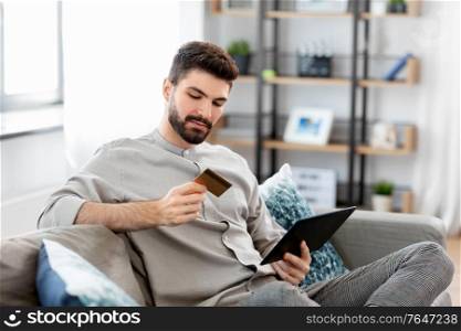 technology, people and online shopping concept - man with tablet pc computer and credit card at home. man with tablet computer and credit card at home