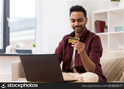 technology, people and online shopping concept - smiling man with laptop and credit card at home. smiling man with laptop and credit card at home