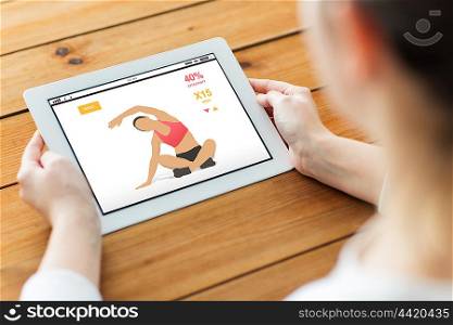 technology, people and sport concept - close up of woman with fitness application on tablet pc computer screen on wooden table
