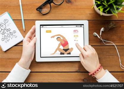 technology, people and sport concept - close up of woman with fitness application on tablet pc computer screen on wooden table