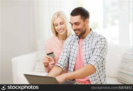 technology, people, e-money and commerce concept - smiling happy couple with laptop computer and credit or bank card shopping online at home