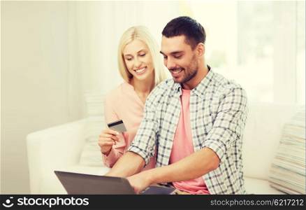 technology, people, e-money and commerce concept - smiling happy couple with laptop computer and credit or bank card shopping online at home