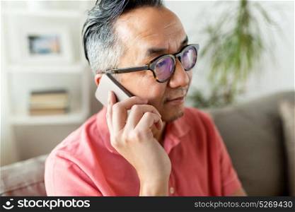 technology, people, lifestyle and communication concept - close up of asian man sitting on sofa calling on smartphone at home. close up of asian man calling on smartphone