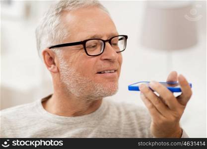 technology, people, lifestyle and communication concept - close up of happy senior man using voice command recorder or calling on smartphone at home