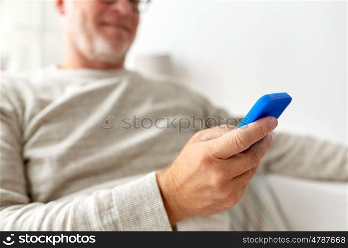 technology, people, lifestyle and communication concept - close up of happy senior man dialing phone number and texting on smartphone at home