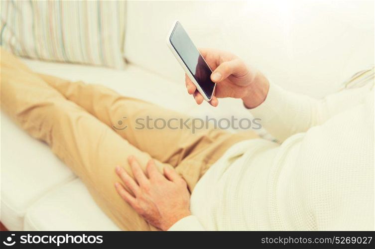 technology, people, lifestyle and communication concept - close up of man with smartphone lying on sofa at home. close up of man with smartphone at home