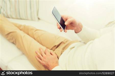 technology, people, lifestyle and communication concept - close up of man with smartphone lying on sofa at home. close up of man with smartphone at home