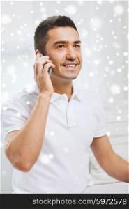 technology, people, lifestyle and communication concept - happy man calling on smartphone at home over snow effect