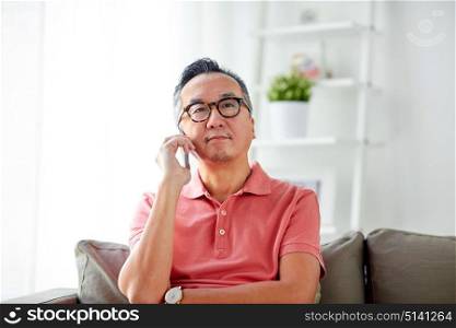 technology, people, lifestyle and communication concept - happy man sitting on sofa calling on smartphone at home. happy man calling on smartphone at home