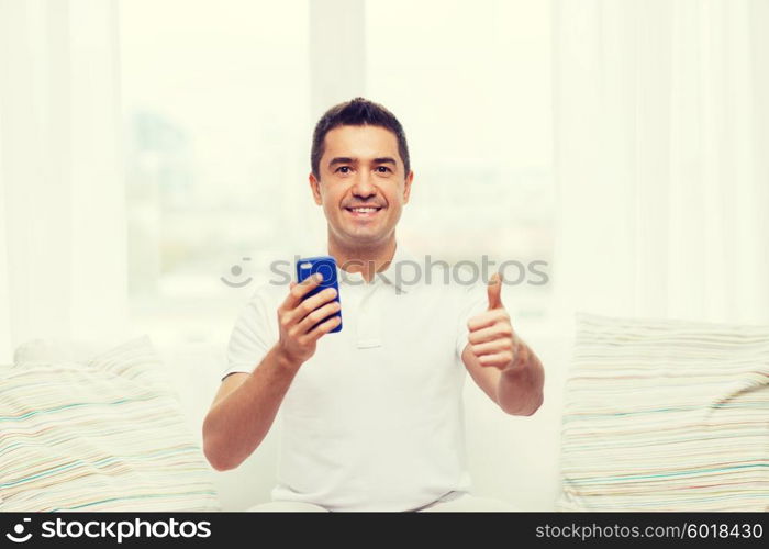 technology, people, lifestyle and communication concept - happy man with smartphone at home