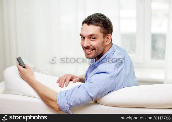 technology, people, lifestyle and communication concept - happy man with smartphone at home