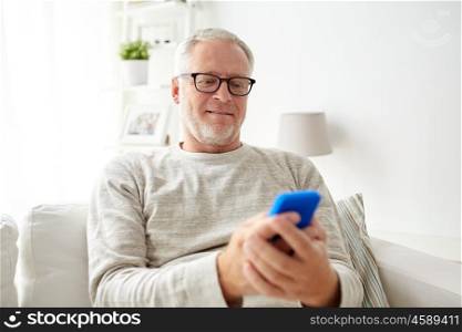 technology, people, lifestyle and communication concept - happy senior man dialing phone number and texting on smartphone at home