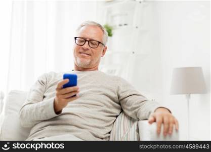 technology, people, lifestyle and communication concept - happy senior man dialing phone number and texting on smartphone at home