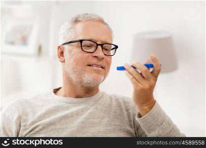 technology, people, lifestyle and communication concept - happy senior man using voice command recorder or calling on smartphone at home