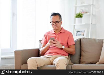 technology, people, lifestyle and communication concept - man with smartphone sitting on sofa at home. man with smartphone sitting on sofa at home