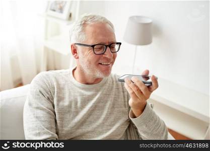 technology, people, lifestyle and communication concept - of happy senior man using voice command recorder or calling on smartphone at home