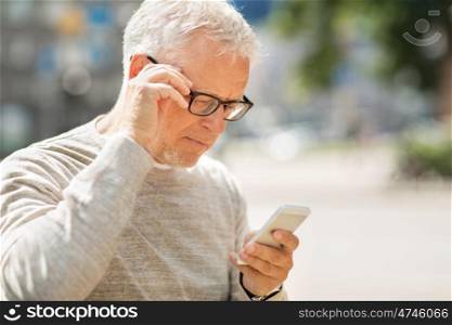 technology, people, lifestyle and communication concept - senior man texting message on smartphone in city