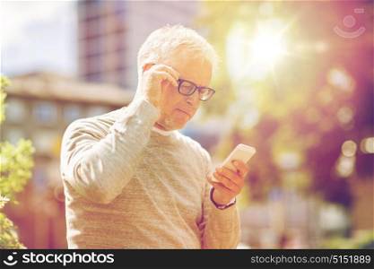 technology, people, lifestyle and communication concept - senior man texting message on smartphone in city. senior man texting message on smartphone in city