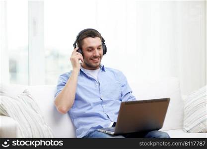 technology, people, lifestyle and distance learning concept - happy man with laptop computer and headphones listening to music at home