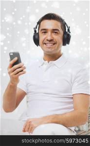 technology, people, lifestyle and distance learning concept - happy man with smartphone and headphones listening to music at home over snow effect