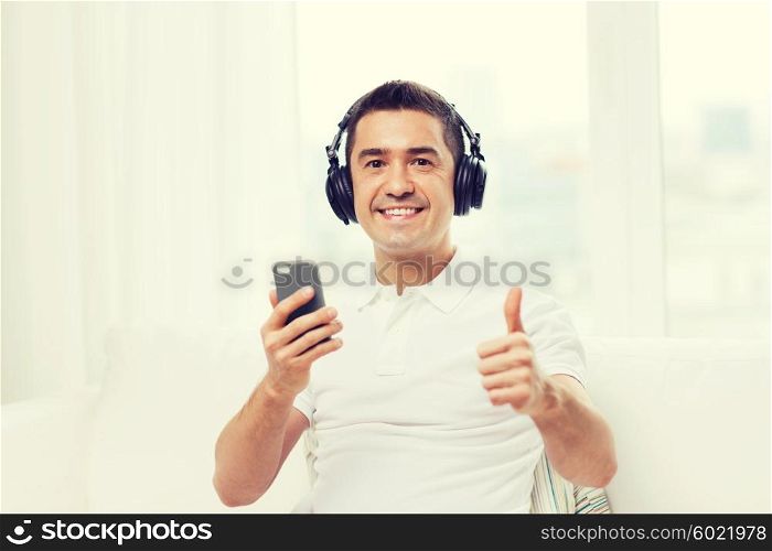 technology, people, lifestyle and distance learning concept - happy man with smartphone and headphones listening to music at home