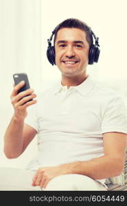 technology, people, lifestyle and distance learning concept - happy man with smartphone and headphones listening to music at home