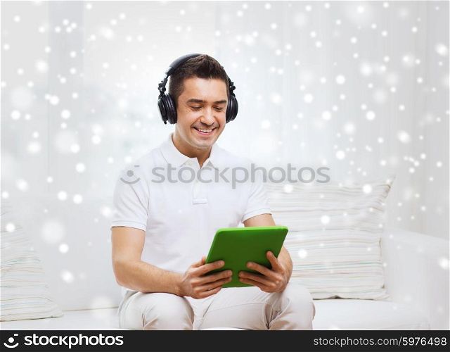 technology, people, lifestyle and distance learning concept - happy man with tablet pc computer and headphones listening to music at home over snow effect