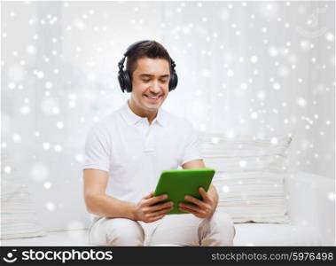 technology, people, lifestyle and distance learning concept - happy man with tablet pc computer and headphones listening to music at home over snow effect