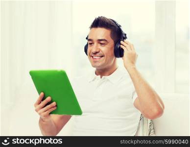 technology, people, lifestyle and distance learning concept - happy man with tablet pc computer and headphones listening to music at home