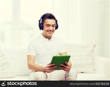 technology, people, lifestyle and distance learning concept - happy man with tablet pc computer and headphones listening to music at home