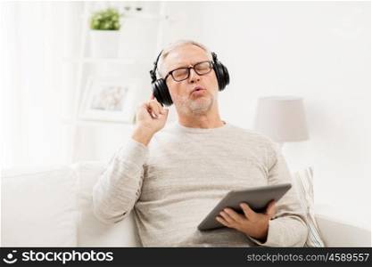 technology, people, lifestyle and distance learning concept - happy senior man with tablet pc computer and headphones listening to music and singing at home