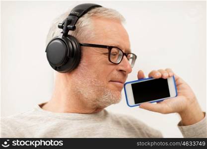 technology, people, lifestyle and distance learning concept - happy senior man with smartphone and headphones listening to music and singing at home