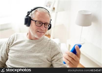 technology, people, lifestyle and distance learning concept - happy senior man with smartphone and headphones listening to music at home