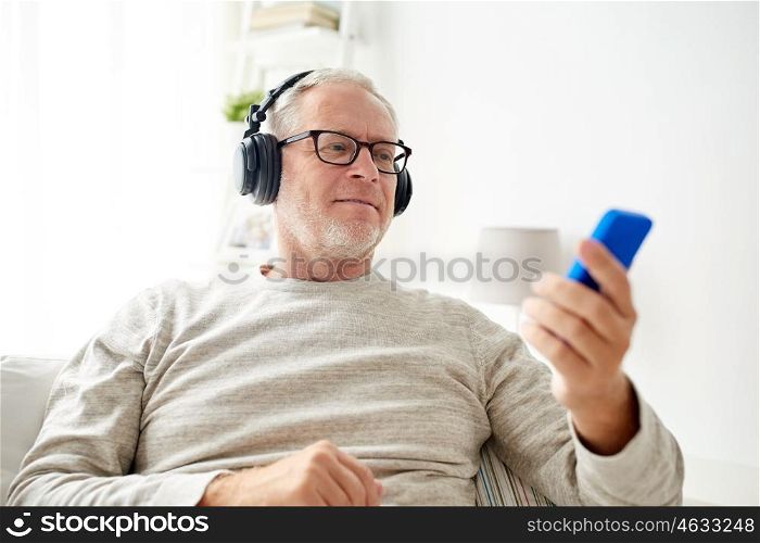 technology, people, lifestyle and leisure concept - happy senior man with smartphone and headphones listening to music at home