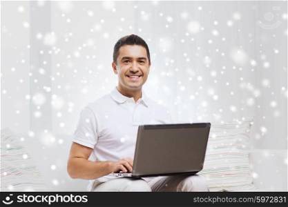 technology, people lifestyle and networking concept - happy man working with laptop computer at home over snow effect