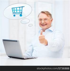 technology, people, oldness, gesture and online shopping concept - old man in eyeglasses with laptop computer at home showing thumbs up and text bubble with trolley