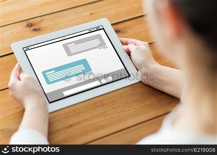 technology, people, social network and communication concept - close up of woman with internet messenger chat on tablet pc computer screen on wooden table