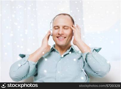 technology, people, winter and leisure concept - smiling man in headphones listening to music at home