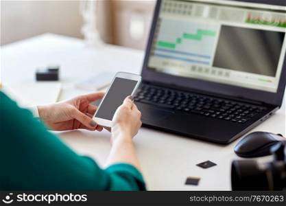 technology, post production and vlog concept - close up of woman with smartphone and laptop computer working at home office. woman smartphone and laptop working at home